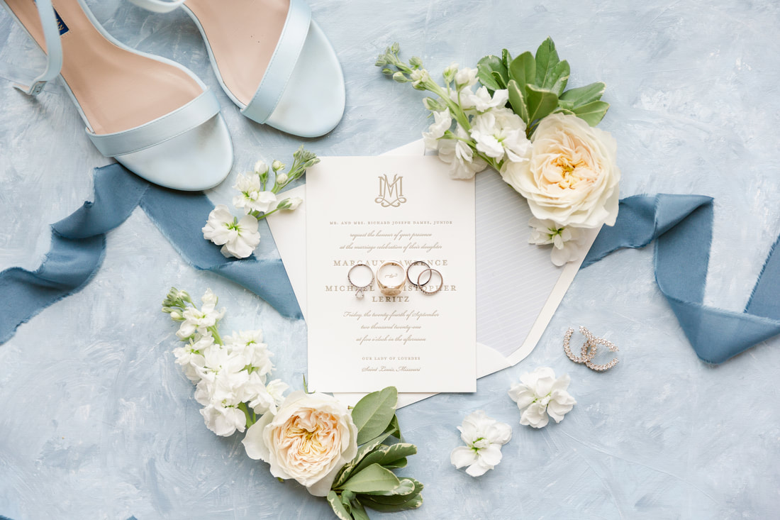 Wedding details photo with rings, invitations, blues and blooms