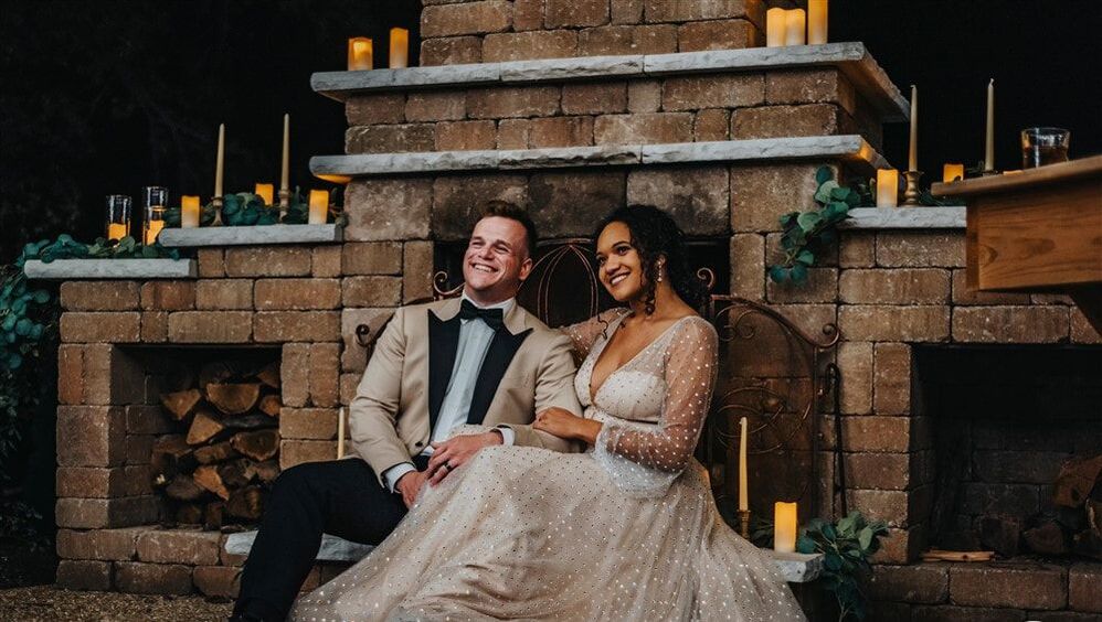 Bride and groom portrait in front of grand candle lit stone fireplace