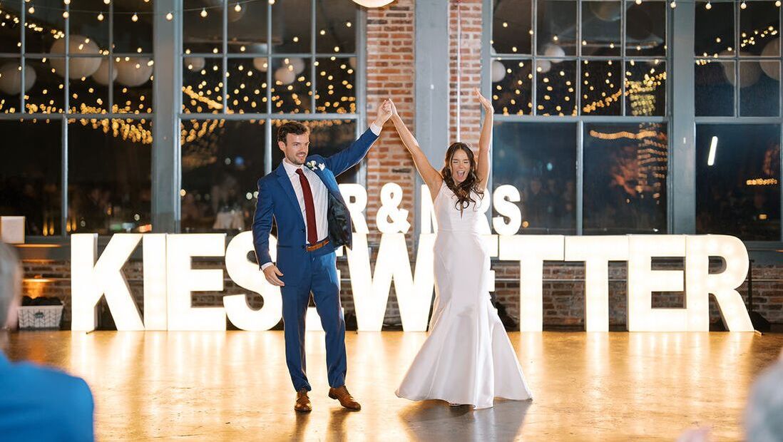 Bride and groom on dance floor with large marquee letters
