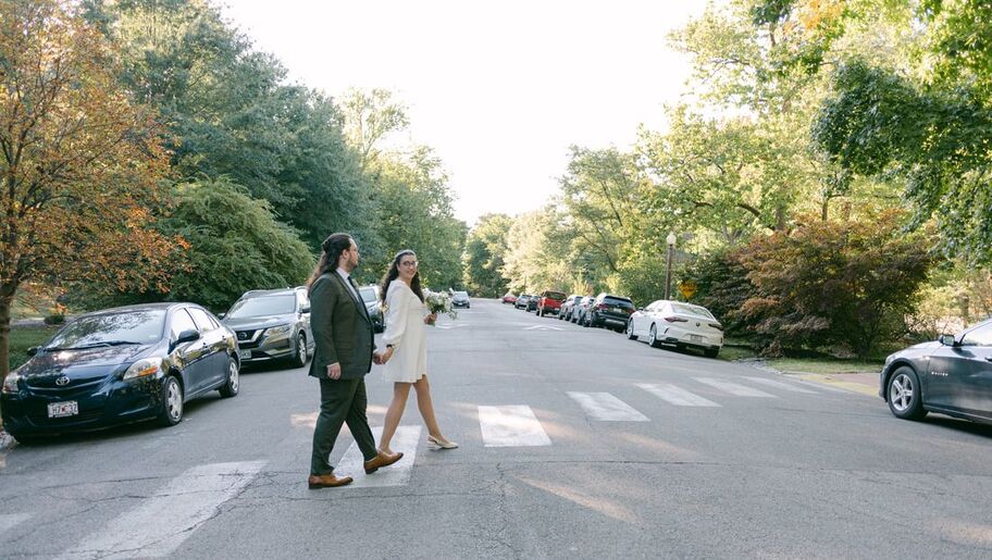 Bride and groom holding hands crossing the street in Tower Grove Park