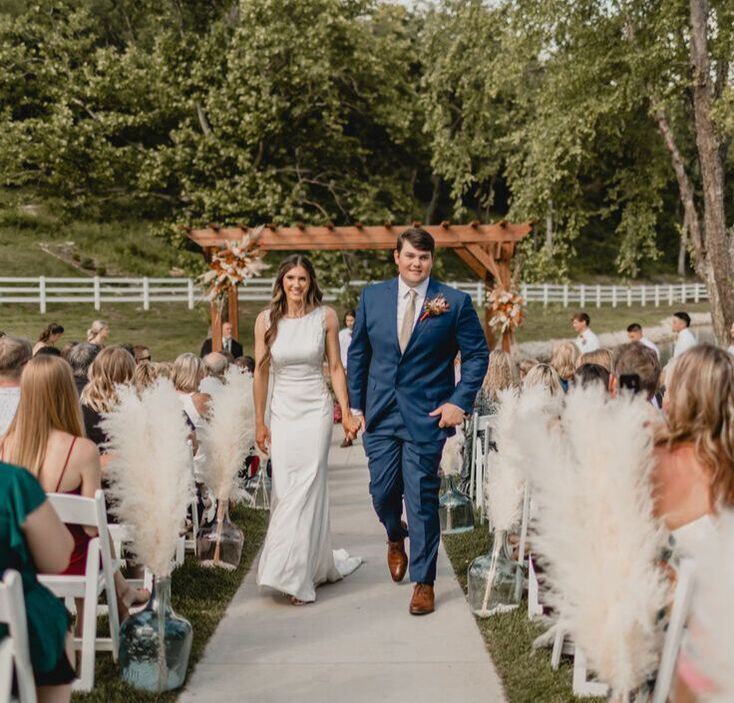 Newlyweds exiting outdoor ceremony aisle
