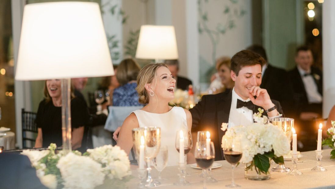 Bride and groom laughing at best man toast in country club ballroom